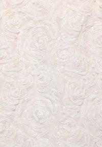 Tissu blanc avec des motifs de rosettes texturées et de petites paillettes brillantes dispersées partout.