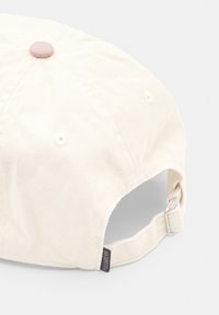 Cremefarvet bomulds-kappe med en rund krone, tekstureret stof, matchende knap på toppen og en justerbar rem på bagsiden med et mærke.