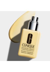 Clinique Lotion Idratante Dramaticamente Differente+, bottiglia quadrata gialla con pompa argentata, logo nero e campione di crema gialla chiara.