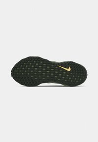 Nike sporta apavu zole tumši zaļā krāsā ar teksturētu rakstu, ko izceļ dzeltenais logotipa elements netālu no papēža.