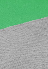 Strukturierten grauen Stoff trifft auf die glatte grüne Oberfläche und schafft einen Kontrast zwischen den beiden Farben. Beide Materialien wirken weich und gewebt.