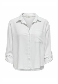 Blusa bianca a maniche lunghe con botonatura frontale, colletto e una singola tasca sul petto; il tessuto appare leggero e leggermente strutturato.