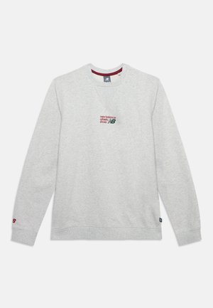 Светлосив суичър с дълги ръкави New Balance с червен и зелен лого текст, центриран на гърдите и малък червен "NB" на маншета на лявата ръка.
