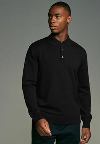 Schwarzer Langarm-Polo-Pullover mit Kragen, ausgestattet mit einer Knopfleiste mit vier Knöpfen und gerippten Bündchen. Weiche Textur, figurbetonter Schnitt.