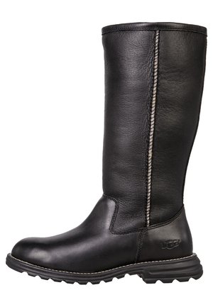 Botte noire en cuir mi-mollet avec semelle robuste, coutures latérales visibles et logo UGG embossé sur le panneau du talon.