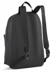 Mochila negra con un tejido suave y acolchado, straps ajustables de nylon, detalle de bolsillo lateral y un diseño sutil en relieve en un lado.