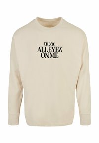 Sweatshirt crem cu mânecă lungă, având inscripții negre "tupac ALL EYEZ ON ME" pe față, cu guler rotund și mansete ribbed.