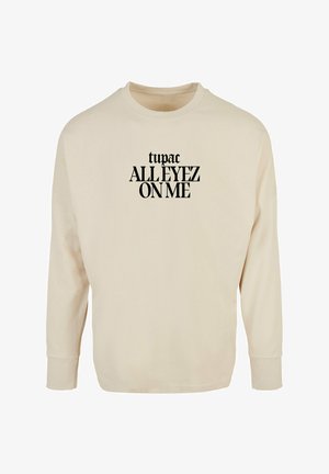 Krém színű, hosszú ujjú pulóver, amelynek elülső részén fekete színű felirat olvasható: "tupac ALL EYEZ ON ME". Kerek nyakkivágása és bordázott mandzsettái vannak.