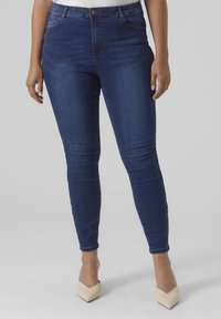 Dunkelblaue, hoch taillierte Skinny-Jeans mit glatter Textur, ausgestattet mit einem vorderen Knopf- und Reißverschluss, dezenter Nahtführung und einer figurbetonten Silhouette.