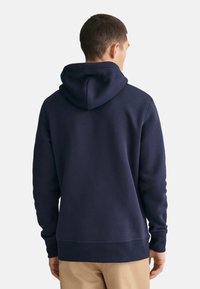 Felpa con cappuccio di colore blu navy con polsini e orlo a costine. Realizzata in un tessuto morbido e testurizzato, presenta una vestibilità rilassata e un cappuccio con cordino regolabile.