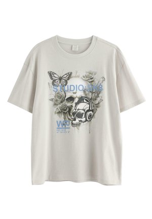 Lysegrå T-shirt med grafik af to kranier, roser, sommerfugle, et kranium med hovedtelefoner og blå tekst "STUDIO SK8" samt koordinater.