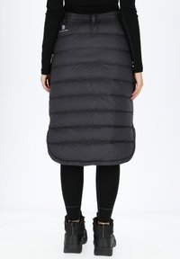 Puffihame mustassa, jossa on tikattu muotoilu ja kaareva helma. Valmistettu kevyestä materiaalista, jossa on joustava vyötärö mukavuutta varten.