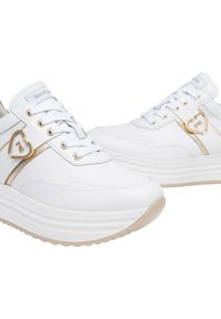 Scarpe da ginnastica bianche con upper in pelle liscia, dettagli dorati e una suola spessa e testurizzata. Presentano un charm a forma di cuore sul lato.