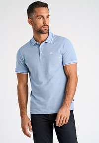 Polo azul claro con un acabado texturizado, tapeta de dos botones y acentos de rayas blancas en el cuello y las mangas.