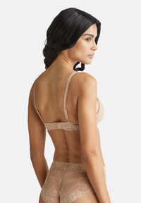 Reggiseno senza ferretti con bordi in pizzo trasparente, spalline regolabili e chiusura a gancio sul retro. Silhouette di intimo riconoscibile con tessuto morbido.