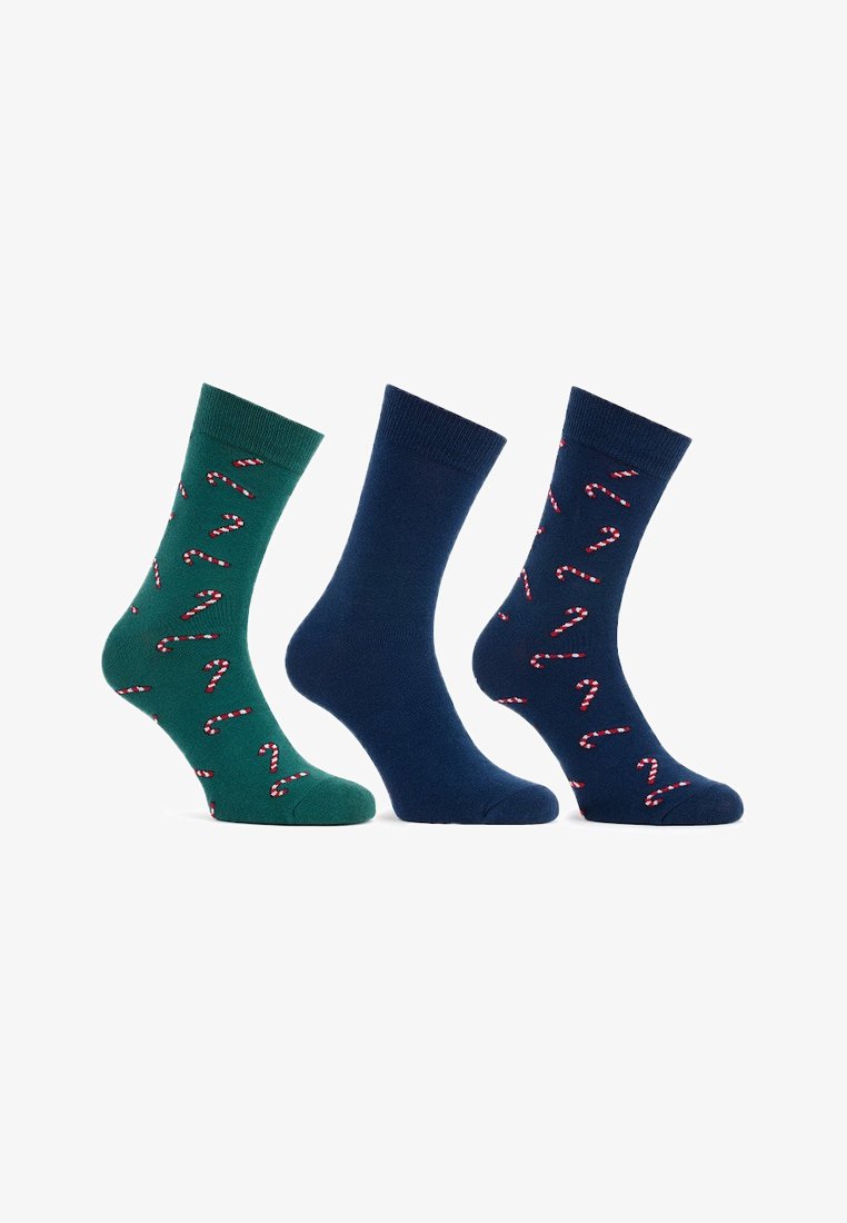 Trzy pary bawełnianych skarpetek: jedna zielona w czerwono-białe wzory cukrowych lasek, jedna granatowa gładka, a druga granatowa z cukrowymi laskami.