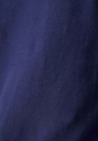 Marineblauwe katoenen stof met een gladde textuur, die subtiele tintvariaties en een lichte glans toont. Geen patronen of opvallende details zichtbaar.