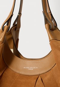 Braune Leder- und Wildleder-Handtasche mit zwei Griffen, plissiertem Design und einem Logo am Kragen. Glatte Textur mit kontrastierenden Akzenten.