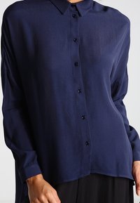 Mörkblå knapp-up skjorta i lätt tyg, med krage, långa ärmar och knappstängning fram, i en avslappnad passform.
