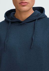 Sudadera azul marino con cordones, de textura suave y ajuste clásico. La tela presenta una superficie lisa y consistente sin patrones.