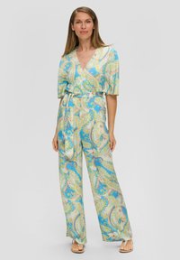 Helles, gemustertes Jumpsuit in Blau, Gelb und Creme. Verfügt über ein Wickeldesign, kurze Ärmel, weite Beine und eine gebundene Taille.