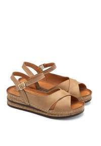Beżowe skórzane sandały z dwoma regulowanymi paskami, krzyżowym wzorem, teksturowaną korkową podeszwą i wyściełaną wkładką dla wygody.