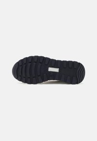 Semelle de chaussure en caoutchouc noir avec une surface texturée, présentant de profonds sillons et crêtes pour une meilleure traction. Design plat avec une couleur uniforme.