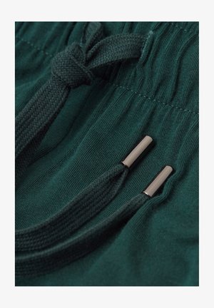 Donkergroene sweatpants met een gestructureerde stof, een elastische trekkoordtaille en metalen aglets op de trekkoorden.