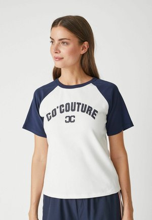 T-shirt a maniche corte con corpo bianco e maniche raglan blu navy. Presenta la scritta "CO'COUTURE" in blu scuro sul petto. Realizzato in tessuto morbido.