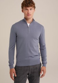 Suéter de punto azul claro con media cremallera, mangas largas y puños acanalados, combinado con pantalones de cuadro gris. Textura suave, detalles mínimos.