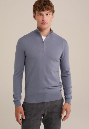Suéter de punto azul claro con media cremallera, mangas largas y puños acanalados, combinado con pantalones de cuadro gris. Textura suave, detalles mínimos.