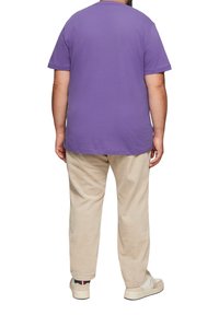 Purple cotton t-shirt with short sleeves, featuring a round neckline. Paired with cream-colored corduroy pants and neutral sneakers.