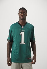 Grøn NFL-trøje med hvidt nummer "1" på forsiden, med sort kant på ærmer og krave, polyester materiale, og Eagles-logo på ærmerne.