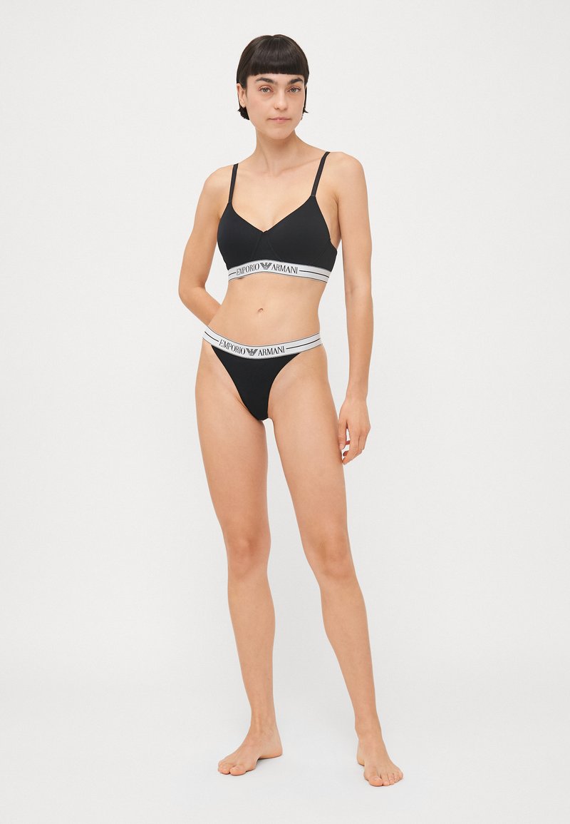 Black bikini set featuring a bralette with adjustable straps and a matching thong. Both pieces have white branded elastic bands.