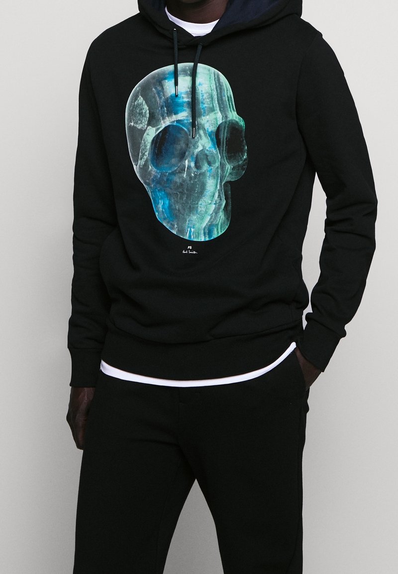 Černá mikina s kapucí s grafikou lebky v modrém odstínu na přední straně. Vyrobena z měkké látky, s kapucí na stažení a žebrovanými manžetami.