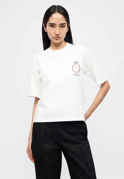 Λευκό βαμβακερό T-shirt με κοντά μανίκια, με τυπωμένο σχέδιο στο αριστερό στήθος και άνετη, cropped εφαρμογή. Φορεμένο με σκούρο παντελόνι.