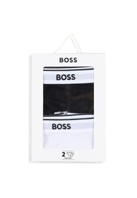 Dve bombažni elastični hlačke v črni in beli barvi z izrazito blagovno znamko "BOSS" in kontrastnimi črtami, zapakirani v belo škatlo z jasnim okencem.