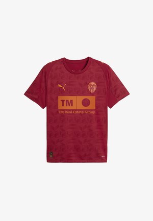 Maillot de sport rouge avec un motif texturé, à manches courtes, logo Puma en or, et un logo de sponsor central en orange avec du texte.