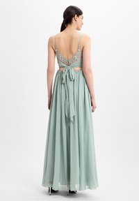 Mintgrünes Kleid mit einem transparenten, bestickten Rücken und einem verstellbaren Taillenband. Es hat Spaghetti-Träger und einen fließenden, geschichteten Rock.