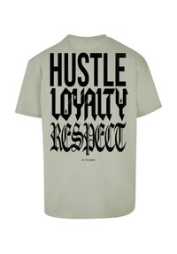 Lys olivengrøn t-shirt med stor sort tekst der står "HUSTLE LOYALTY RESPECT" på ryggen, med en glat bomuldsstruktur.