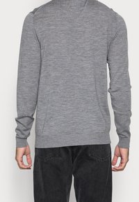 Pull à manches longues gris en tissu tricoté doux. Présente un col rond et des poignets côtelés, avec une texture unie sur toute la surface.