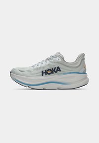 Sapatilha de corrida cinza claro com um upper de malha respirável, detalhes em azul, marca HOKA e uma sola espessa e acolchoada para suporte.