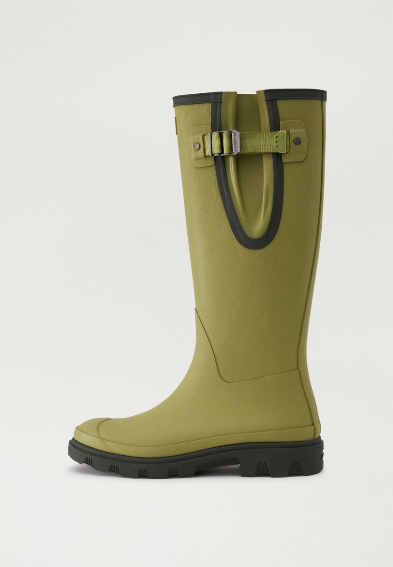 Bota de lluvia de goma verde con un acabado texturizado, acentos negros alrededor de la parte superior y un detalle de correa y hebilla en el lado.