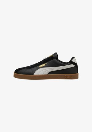 Zwarte lage Puma-sneaker met witte streep, gumzool, gouden Puma-logo's aan de zijkant en tong, en zwarte veters, zijaanzicht.