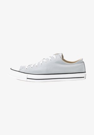 Gray canvas sneaker with white rubber toe cap, black stripe along the sole, and white lace eyelets. Flat laces secured in place.