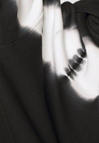 Tela de tie-dye en blanco y negro, con una textura de algodón suave, que presenta patrones abstractos creados al mezclar colores oscuros y claros.
