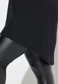 Black short-sleeved top made of cotton paired with shiny black leggings. The top has a rounded hem, and the leggings are form-fitting.