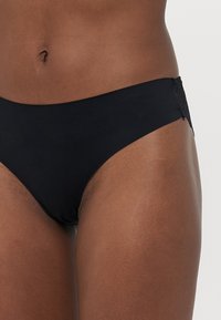 Svart bikiniunderdel i mjuk tyg, med en spetsdetalj på baksidan. Klassisk låg midja design med minimalistisk täckning.