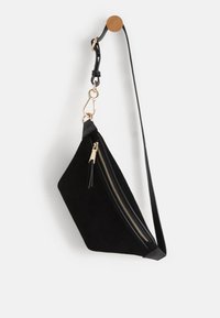 Bolso de ante negro con forma triangular, cremallera dorada y asa de cuero desmontable. Cuenta con un pequeño borlas de cremallera y acentos de hardware dorado.