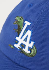Blaues Cap mit einem grünen Dinosaurier und einem weißen "LA"-Logo in Stickerei. Es hat einen strukturierten Stoff und einen gebogenen Schirm.